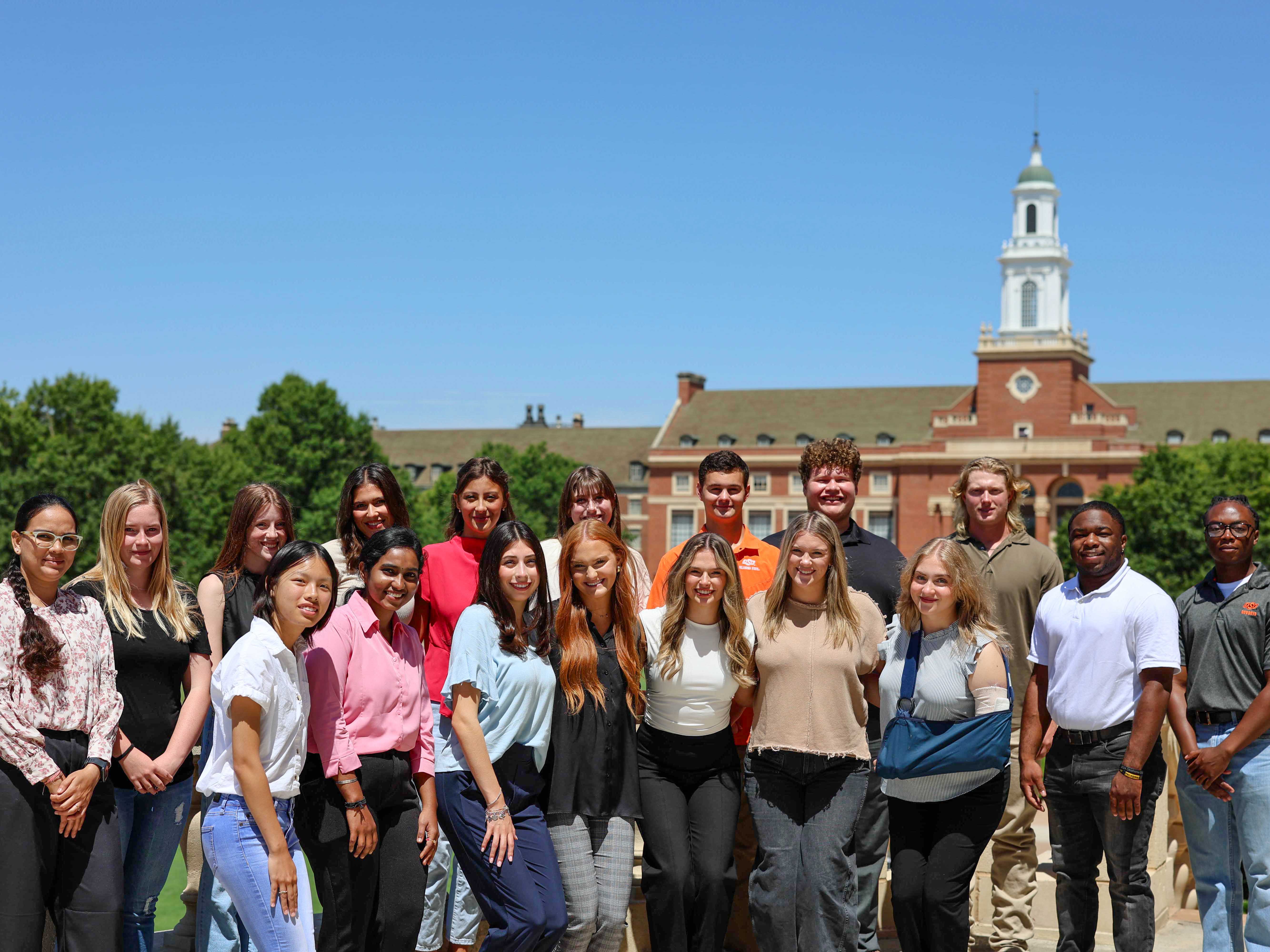 A group photo of InternOSU students on the balcony of the Student Union with the Edmon Low Library in the background.