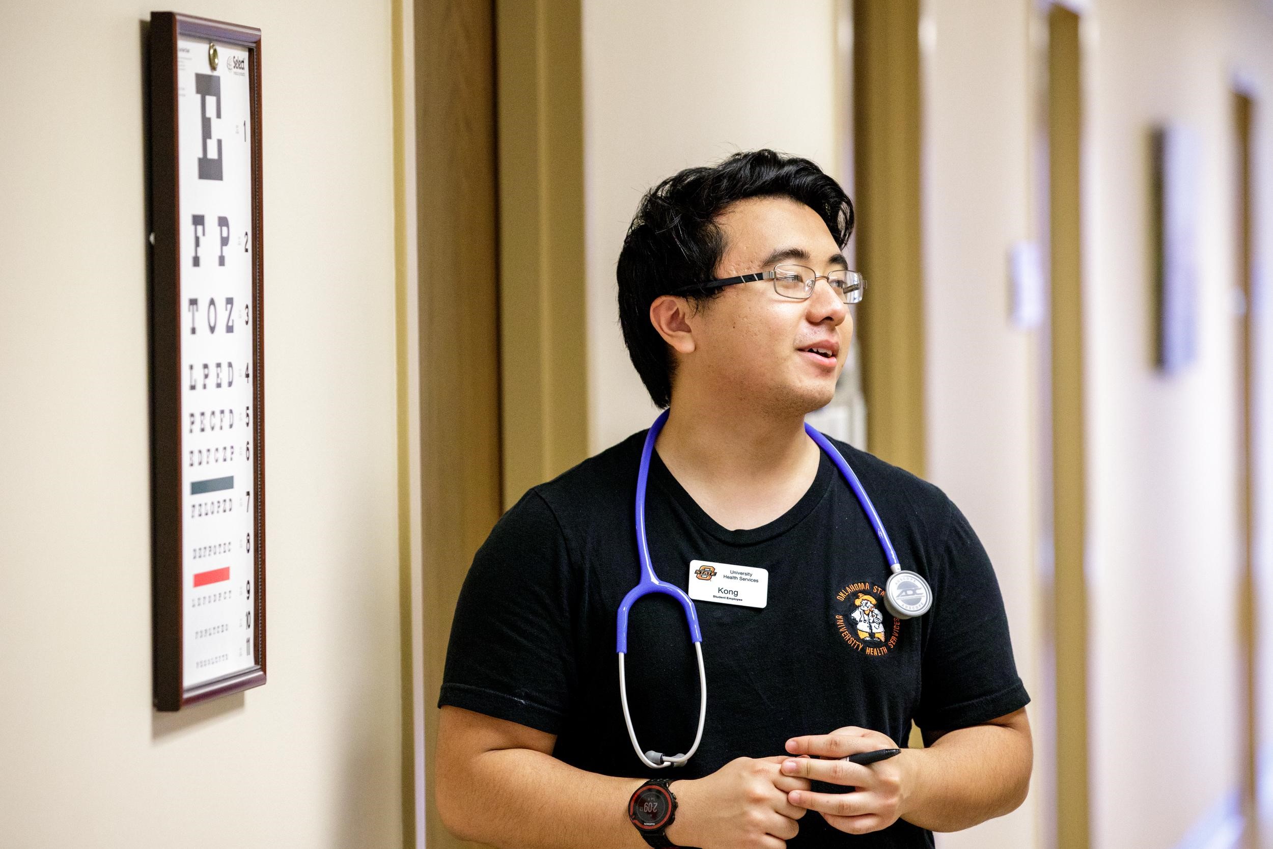 A man in scrubs is walking down a hallway at the University Health Clinic